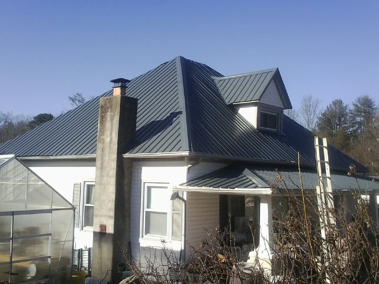 Dark blue standing seam metal roof on a white farmhouse with dormer — Slate & Tile Roof Repair by Roofing Brothers in Rebersburg
