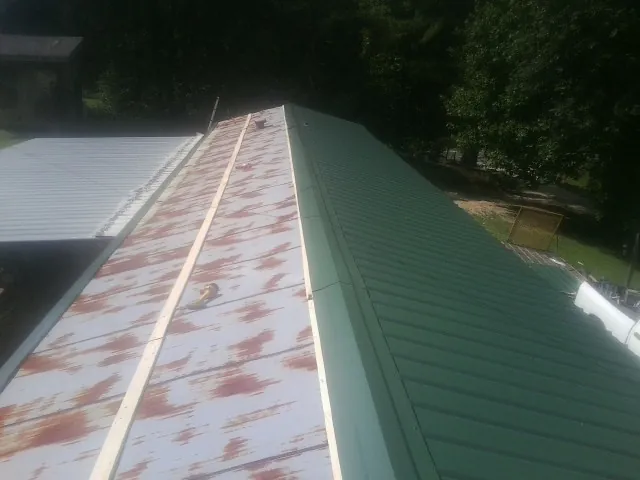 Old rusted panels beside newly installed green metal roofing — Wind Damage Roof Repair by Roofing Brothers in Rebersburg