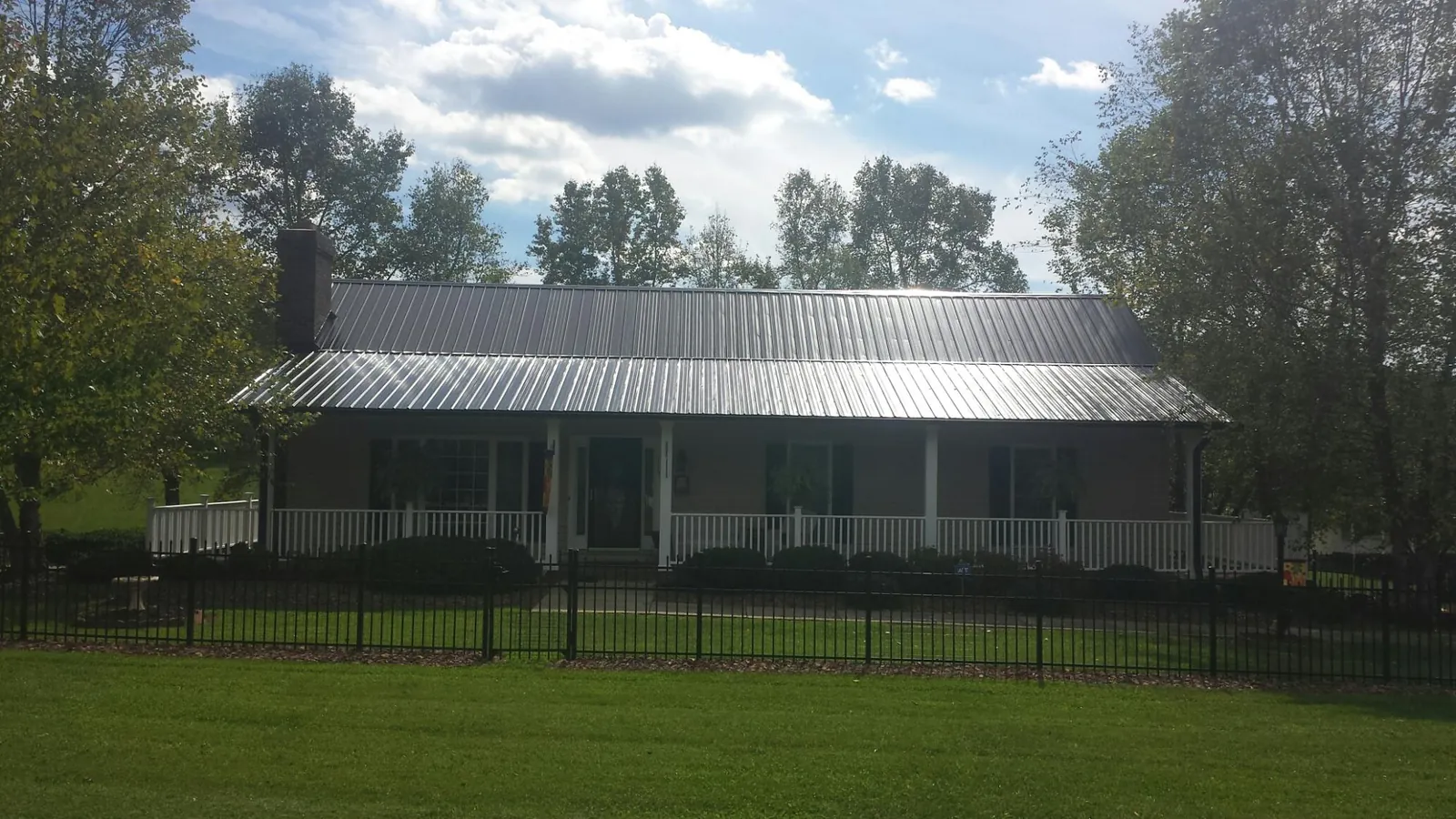 Gray metal roof on a brick ranch with a full width front porch — Gutter Guard Installation work by our crew in Rebersburg