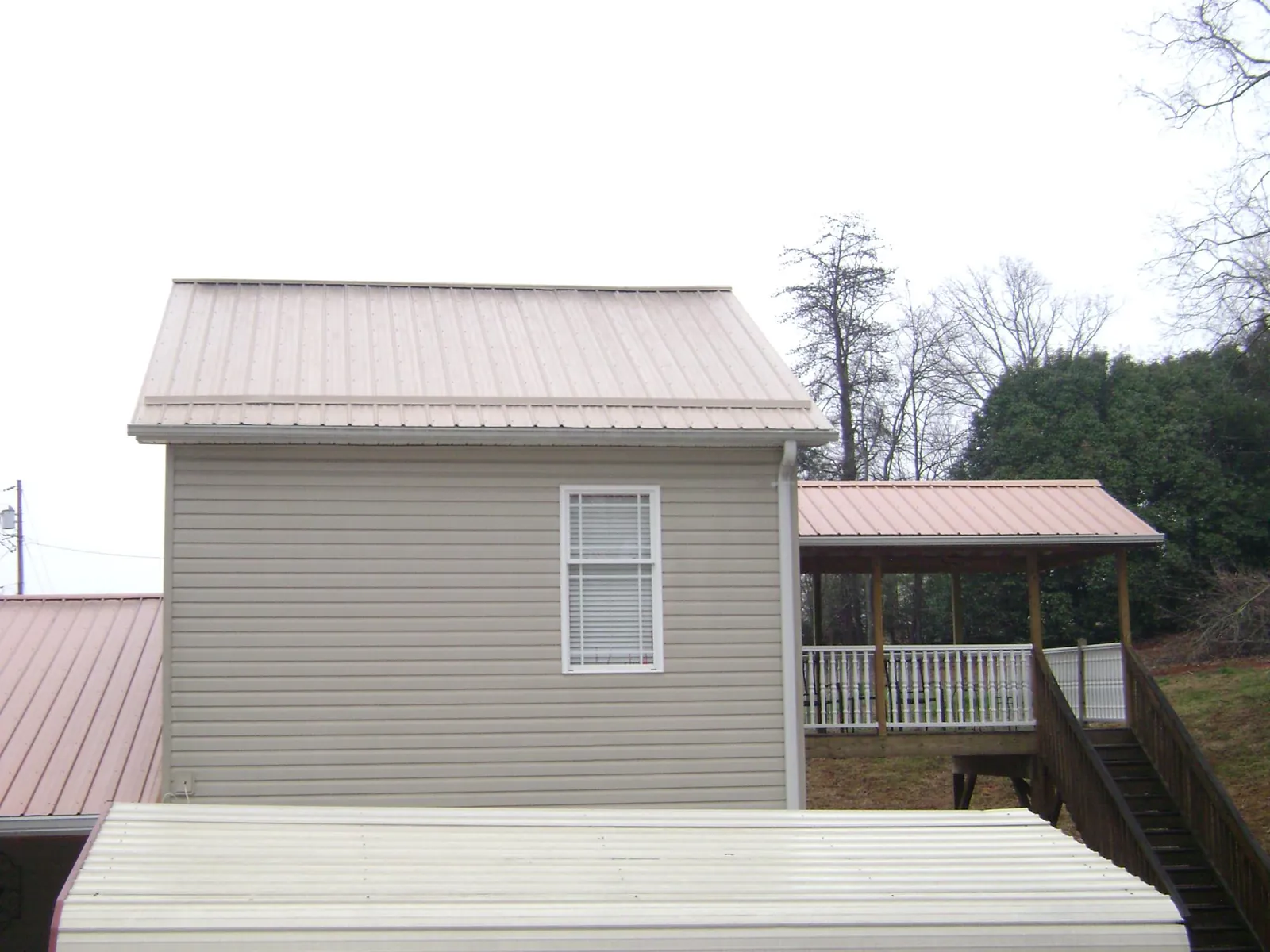 Tan metal roofs on a two story addition and attached porch, from a Roof Replacement job in Rebersburg