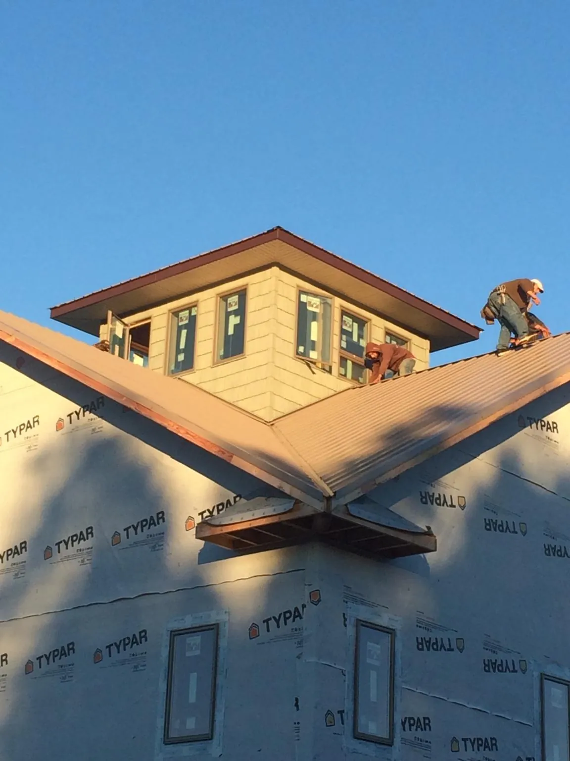 Roofers working around a rooftop cupola on a new metal roof at sunset — Roof Waterproofing in Rebersburg by Roofing Brothers